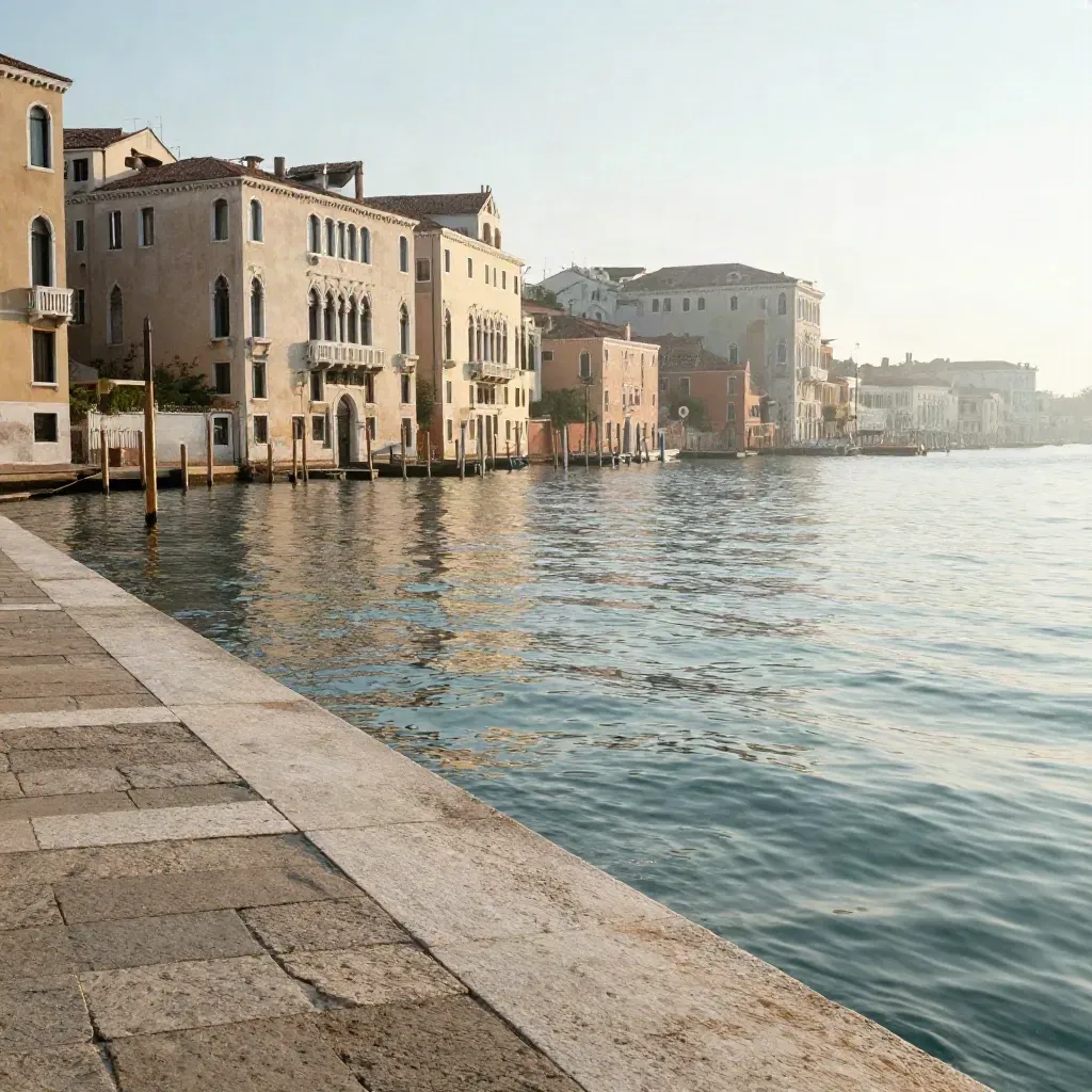 Palazzi veneziani sull’acqua lagunare all’alba, con foschia dorata e riflessi turchesi.