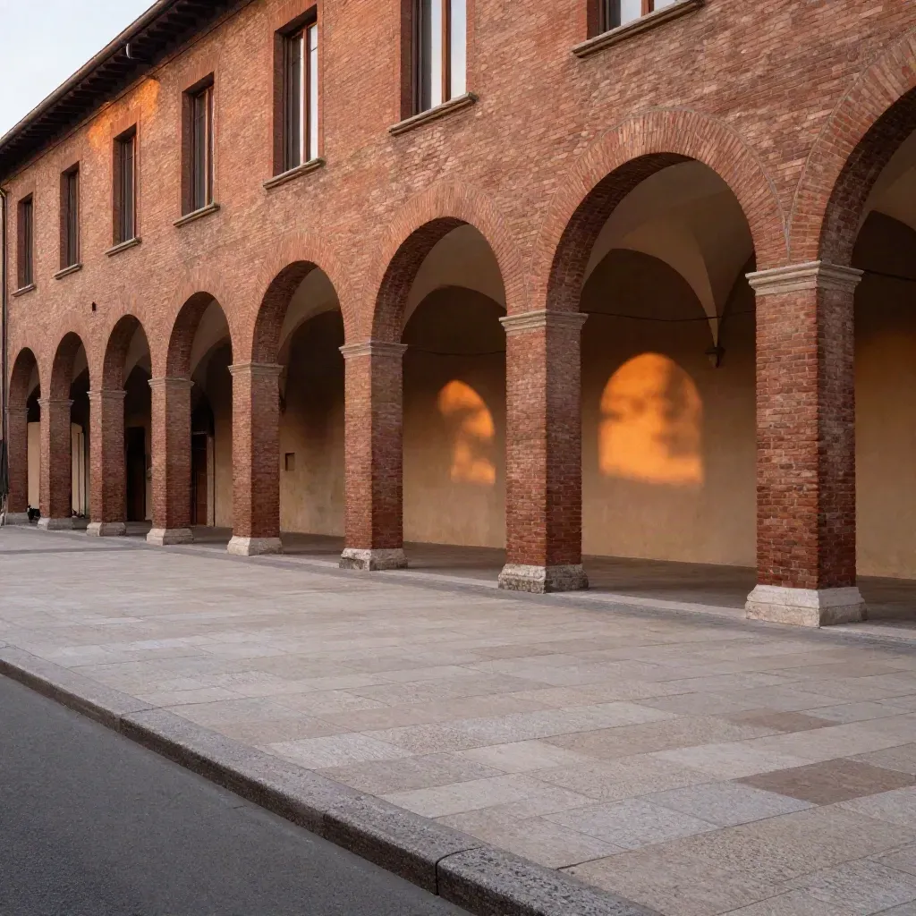 Arcate in terracotta di Bologna illuminate dalla sera, con pavimento chiaro e atmosfera umida.